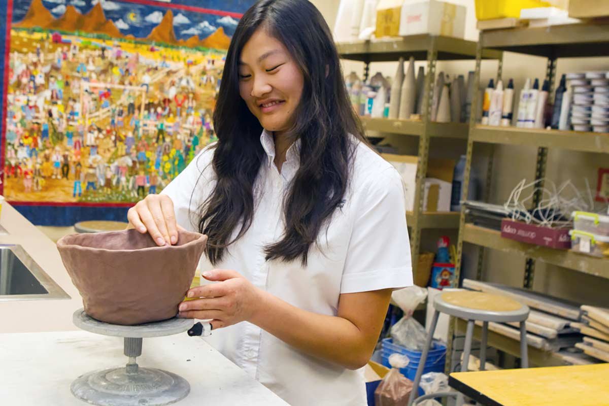 Girl working clay on wheel