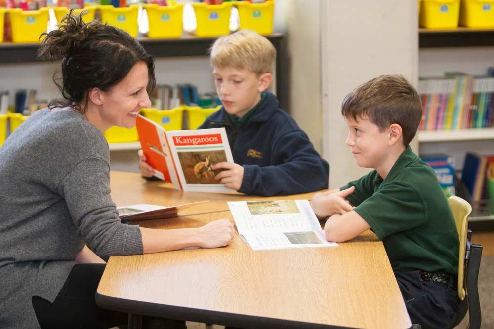 Teacher sitting at desk with two students
